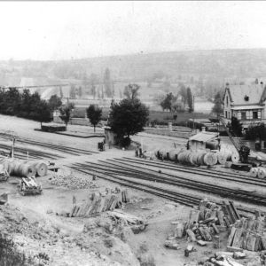 Kottenheim um 1900. Links im Bild ist der Bahnhof zu erkennen. Entlang der Gleise warten zahlreiche Mühlsteine auf ihren Abtransport.