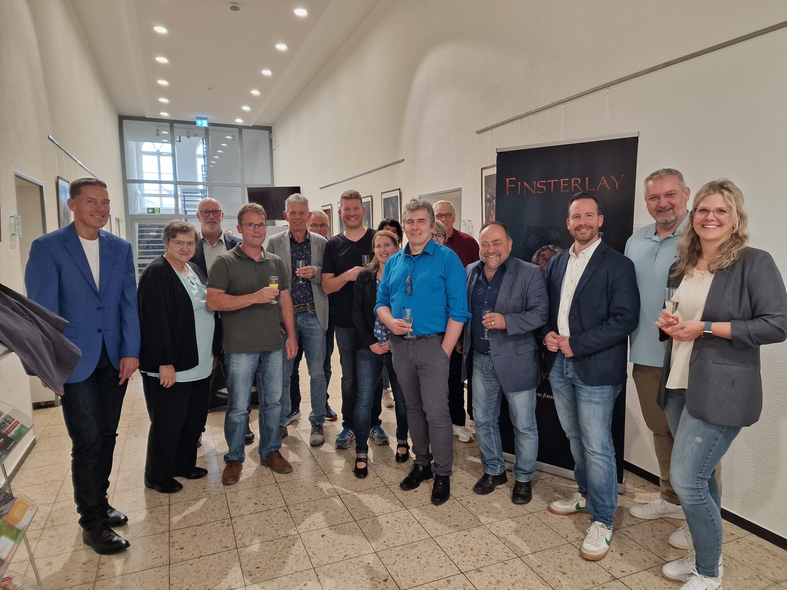 Eine Gruppe von Besuchern im Foyer der Verbandsgemeinde Vordereifel bei einer Ausstellungseröffnung.