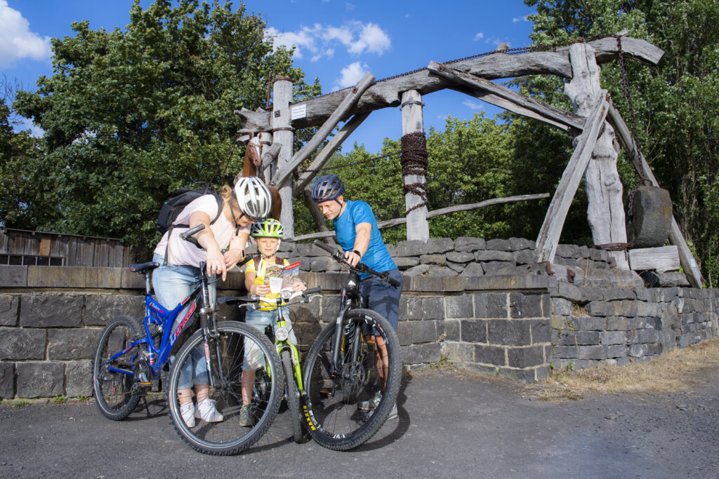 Familie mit Fahrrädern vor einem Göpelwerk.