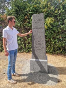Laudator Nicolas Junglas steht neben dem Meilenstein Mühlsteinrevier RheinEifel